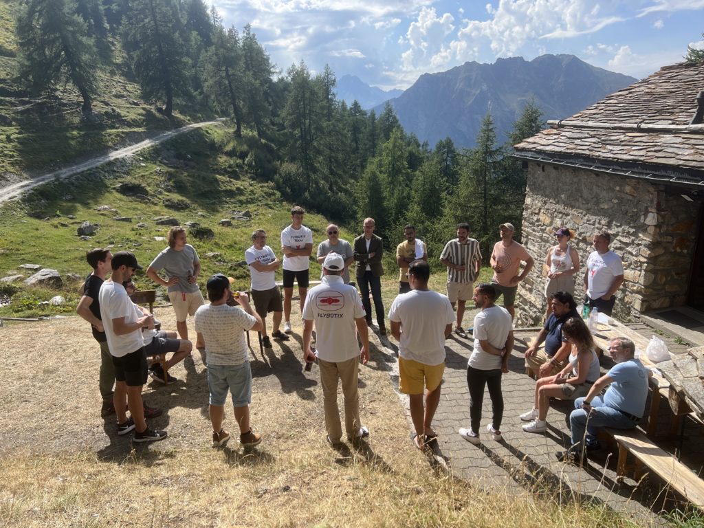Group of Flybotix employees standing in a circle in Swiss mountains