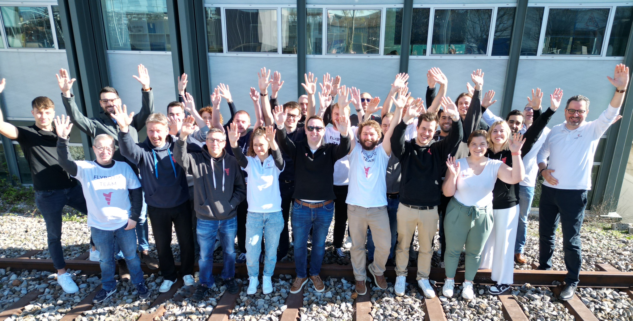 Group picture of Flybotix employees outside with hands raised