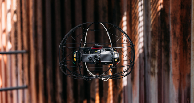 Flybotix ASIOX Drone flying in front of rusted metal background.