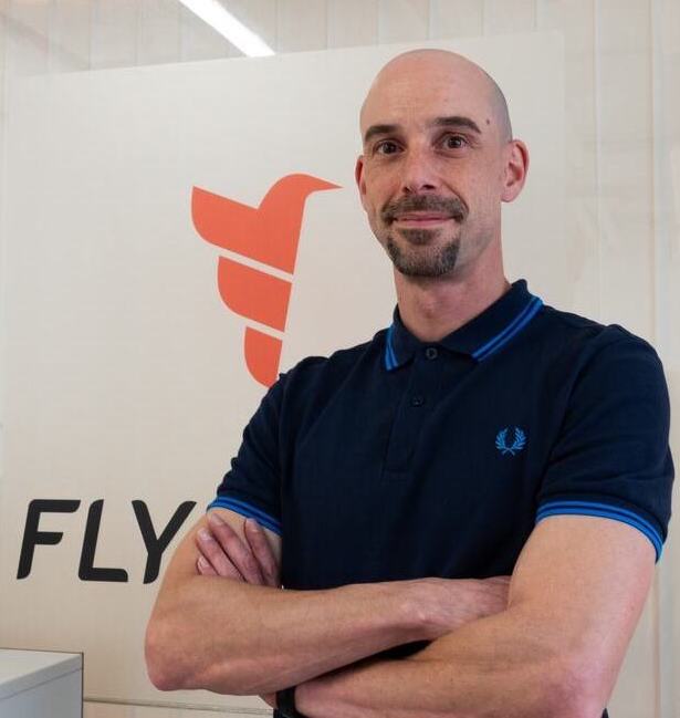 Cedric Hanzi standing in front of Flybotix logo.