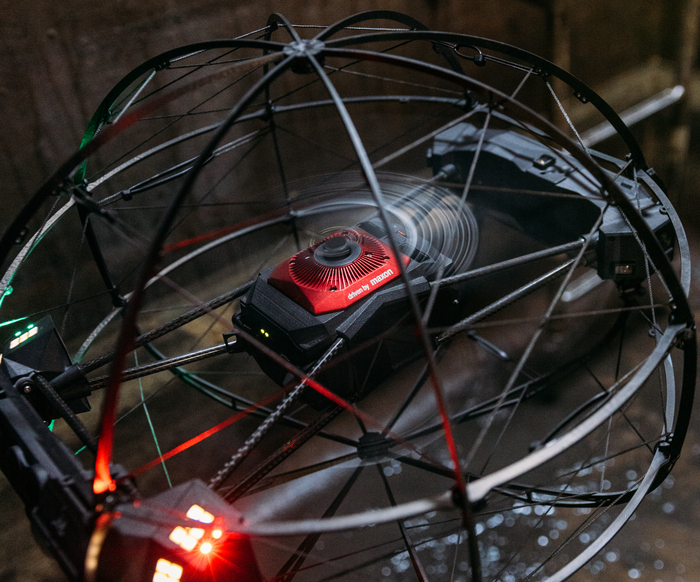 Flybotix ASIO X drone on the ground with propellers in motion.